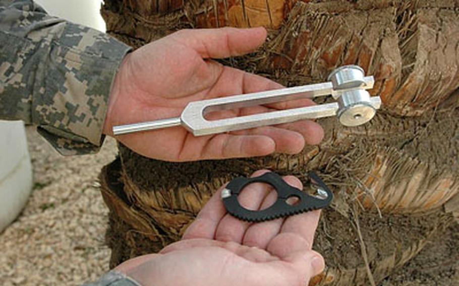Cpt. Arne Oas, 35, a physician’s assistant, holds two "field expedient" tools used the FOB Loyalty aid station team: a tuning fork (left), to diagnose fractures, and a "rescue hook," or seat-belt cutter, to quickly remove clothing and body armor.