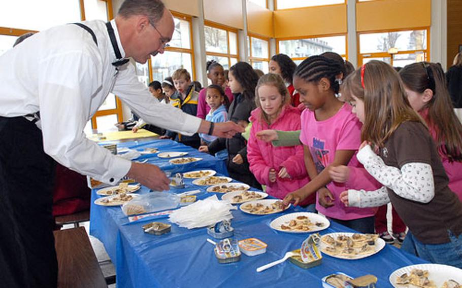 Darmstadt Elementary School principal Russ Claus passes out crackers with sardines on them to children on Wednesday, during Sardine Day.