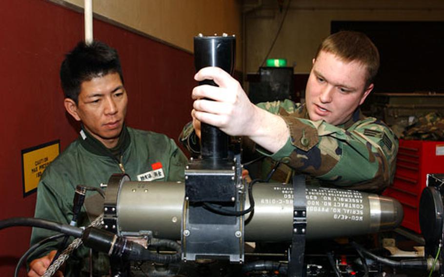 Senior Airman Benjamin Sneyd, 35th Maintenance Squadron, instructs Technical Sergeant Hiroyuki Asakura how to test an AIM-9 missile guidance control system. Asakura is here as part of the bilateral exchange program to strengthen ties between U. S. and Japanese air forces.