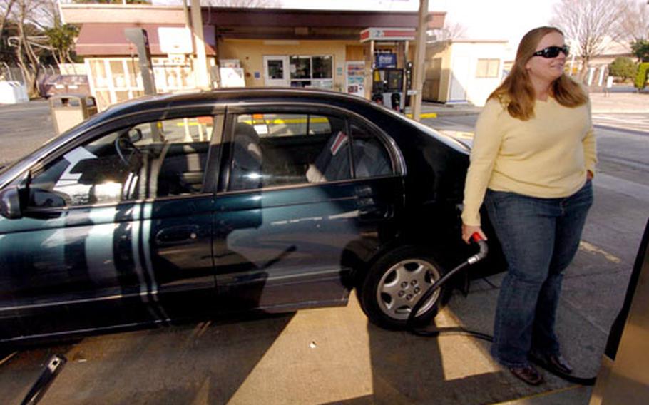 Sharron Todd pumps gas at the west-side station at Yokota Air Base, Japan, on Thursday. AAFES gasoline prices have dropped in the Pacific.