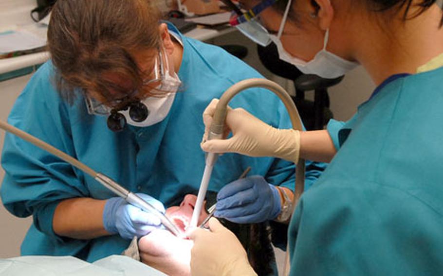 Dr. (Capt.) Amanda Nelson, left, prepares a tooth for a crown for Pfc. Nathaniel von Beitler at the Darmstadt, Germany, dental clinic as Rita Marshall assists.