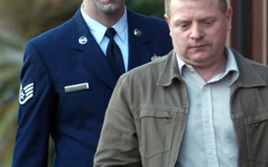 Staff Sgt. Joseph A. Spaulding is shielded by an unknown man as he walks to the RAF Mildenhall courtroom to hear his sentence on Friday.