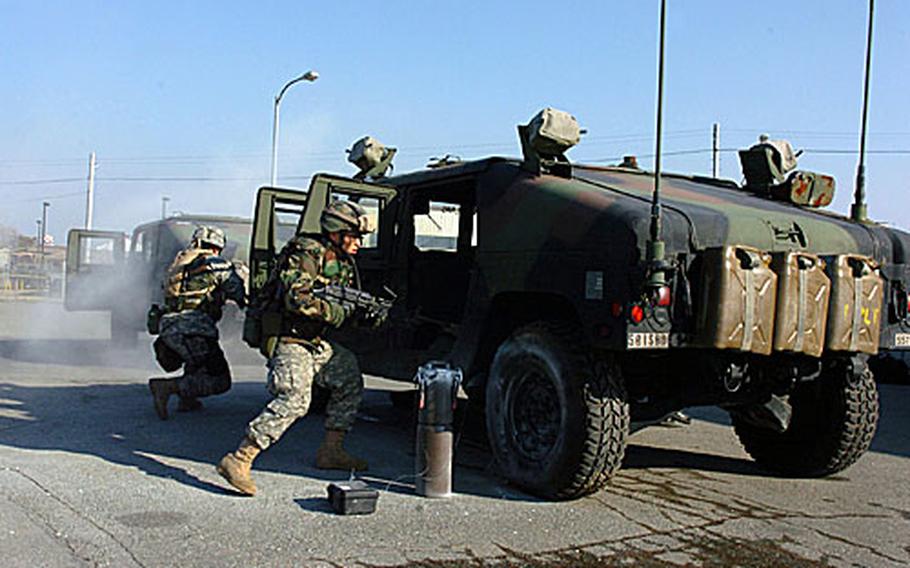 At Camp Humphreys, South Korea, on Jan. 18, members of the 557th Military Police Company stage for an Army photographer a partial reenactment of training they underwent earlier on how to react to roadside bombs. Cylinder in foreground is an improvised explosive device simulator, which the unit plans to make frequent use of in future IED training. The soldiers are Pfc. Kang Seok-jin, right, and Pfc. Carlos Whitehead.