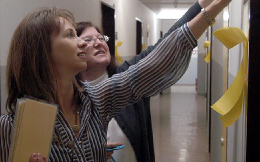 Dawn Eldred, left, and Denise Walker post signs next to doors Friday in a barracks that will soon house soldiers of the 501st Forward Support Battalion. The soldiers have spent more than a year in Iraq, and are expected to return before the end of the month.