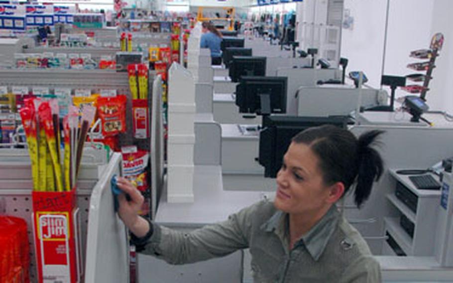 Uli Schendel, a cashier for the new post exchange in Böblingen, Germany, cleans a register area on Friday in preparation for the grand opening.