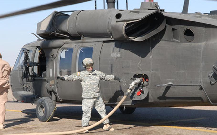 Pfc. Salina Ward of the 209th Aviation Support Battalion, 25th Infantry Division, gestures to a fellow soldier as she fills the tank of a Black Hawk helicopter on Camp Speicher, near Tikrit.