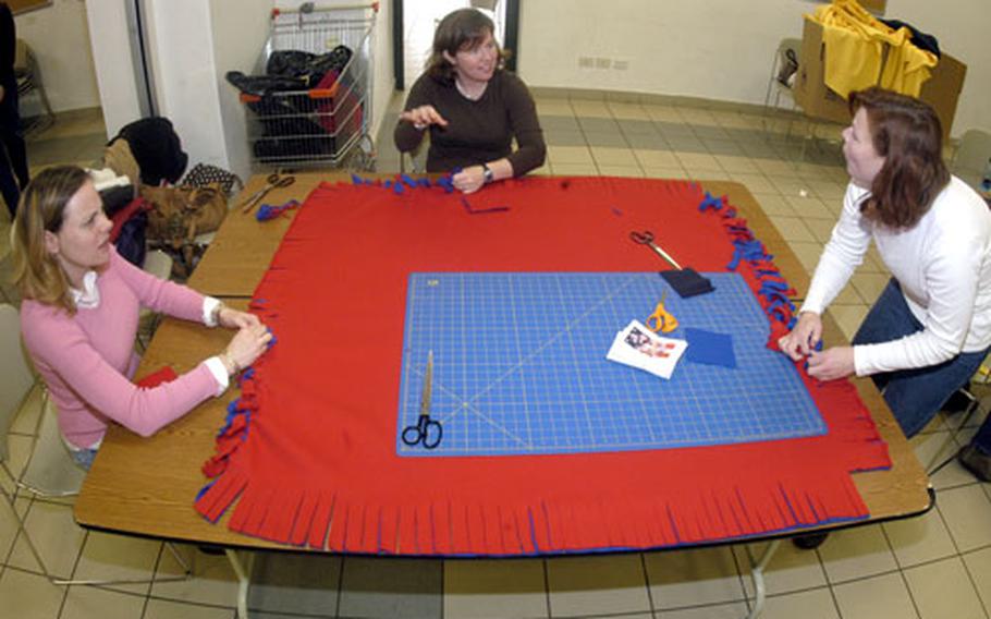 Carrie Schultz, left, Patty Blaser, center, and Lorri Brito chat Monday as they volunteer their time to tie together "no sew" fleece blankets that will be shipped from Naples, Italy, to a U.S. military medical treatment facility in Balad, Iraq, to be given to wounded troops there.