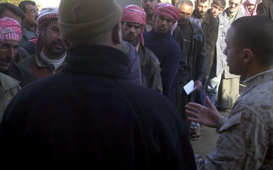 Marine Staff Sgt. Andres Quinones, right, talks with Iraqi men lined up outside the Haditha Civil Military Operations Center with the help of an interpreter. The center is open six days a week and has been seeing about 50 Iraqis a day.