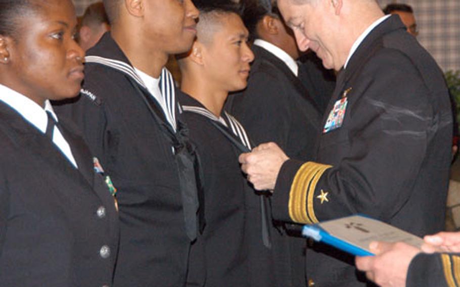 Commander, Naval Forces Japan, Rear Adm. James D. Kelly presents Petty Officer 1st Class Keith Jones, a yeoman at CNFJ a Navy Achievement Medal and offers congratulations for his hard work and achievement.