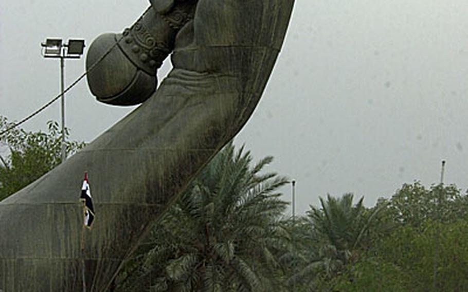 U.S. soldiers drive past the so-called "Hands of Victory" monument in downtown Baghdad in December 2004. According to news reports, Iraqi officials have begun dismantling the structure, which was commissioned by Saddam Hussein as a memorial for the Iraq-Iran war of the 1980s.