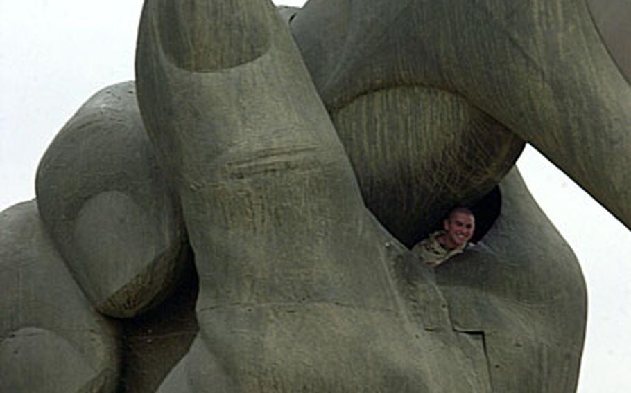 A U.S. soldier poses for photos inside the so-called "Hands of Victory" monument in downtown Baghdad during a brief stop there in December 2004. The monument, one of the most visible of Iraq&#39;s monuments and long a popular "tourist" spot for troops in the Green Zone, is being dismantled by the Iraqi government.