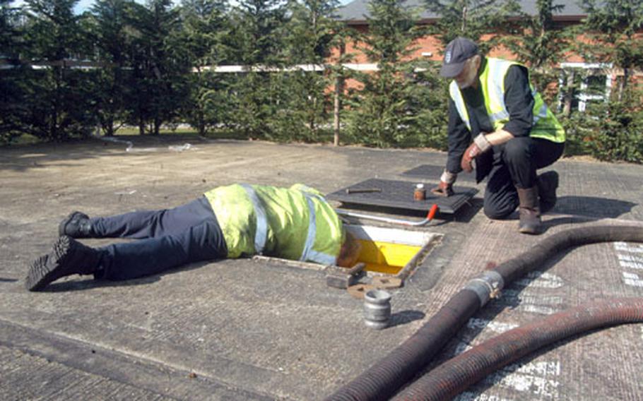 Bob Terry watches Cliff Kingham as he locks up a fuel storage tank after they removed about 32,500 liters of fuel from RAF Mildenhall&#39;s gas station following tests that showed that its fuel was contaminated. Both are from the Bob Terry haulage company.