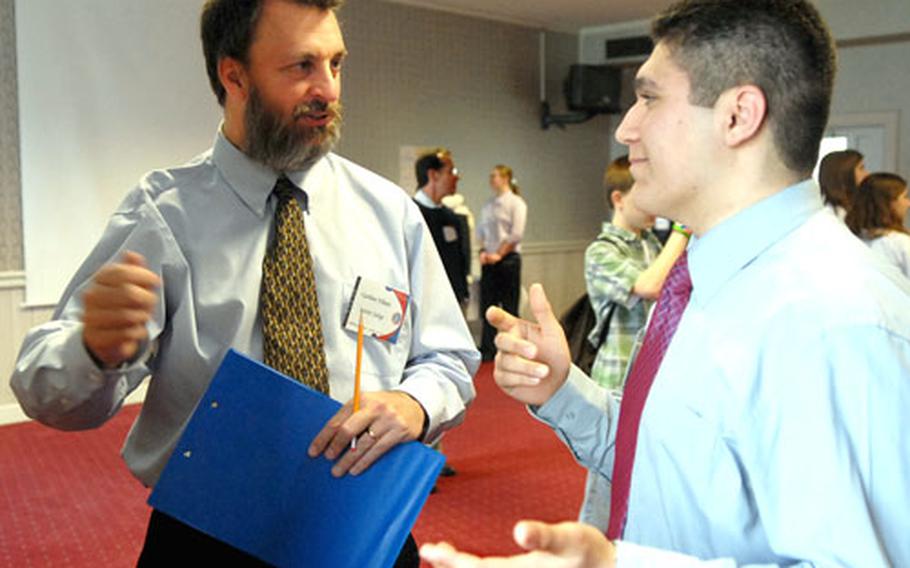 Gorden Videen, left, judge and keynote speaker at DODDS European Junior Science and Humanities Symposium, discusses Davide Chiericoni's poster presentation. Chiericoni, a Naples (Italy) High School student, was one of about 90 middle school and high school pupils attending the symposium.