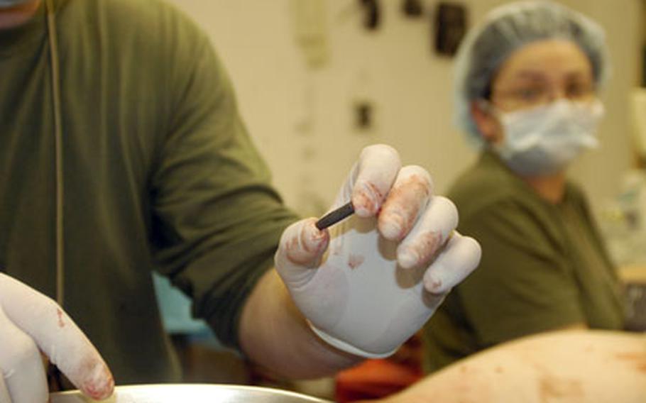 Dr. (Lt. Cmdr.) Chris Carr inspects a bullet taken from the groin of a Marine who had been shot in the leg. The bullet was removed by Dr. (Lt. Cmdr.) Angela Earley, a trauma surgeon (not pictured).