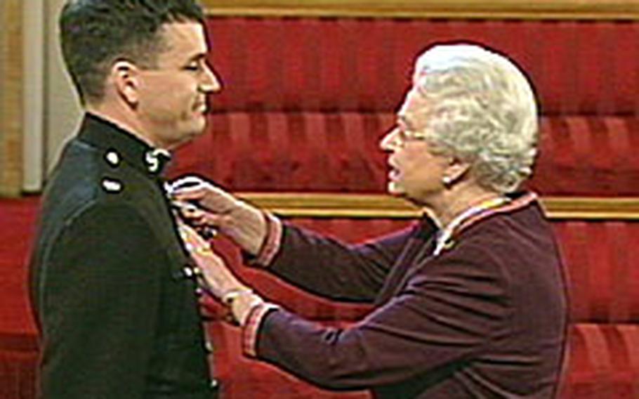 Queen Elizabeth II presents U.S. Marine Maj. William D. Chesarek Jr. with the British Distinguished Flying Cross in a ceremony at Buckingham Palace Wednesday. Chesarek is the first American to receive the honor since World War II.