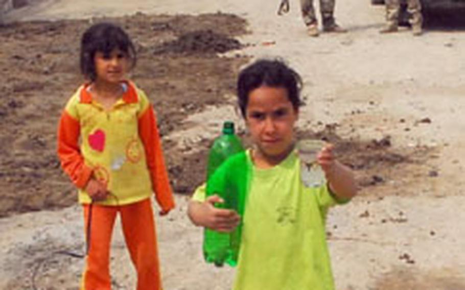 A young Iraqi girl offers a glass of water to a joint patrol of U.S and Iraqi soldiers in the Zafaraniyah neighborhood of east Baghdad recently.