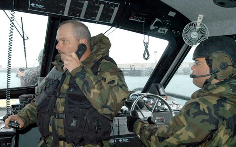 Chief Petty Officer Steve Colley, left, coordinates the movement of a formation of multiple Dauntless Patrol Craft in Busan Harbor during a training exercise Tuesday while Petty Officer 1st Class Rick Chavez controls the craft.