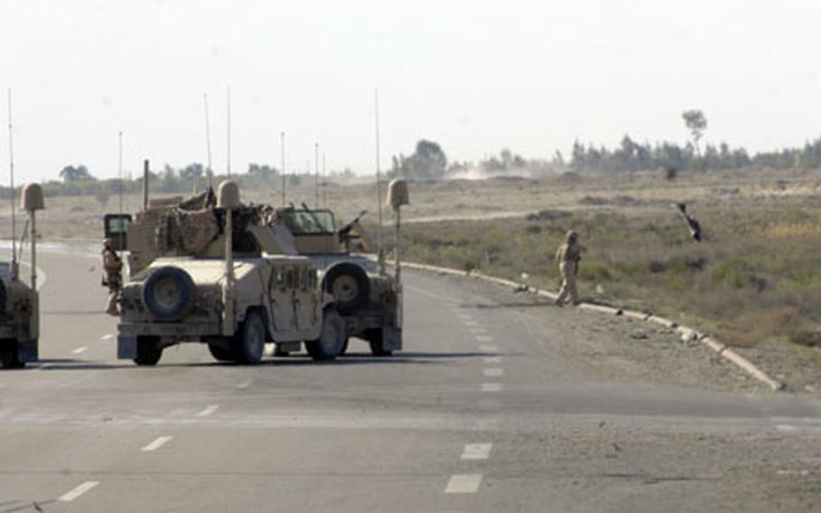 After determining Tuesday that a muffler in the middle of a major highway was not a roadside bomb, a member of an explosive ordnance disposal team chucks it onto the shoulder of the roadway.