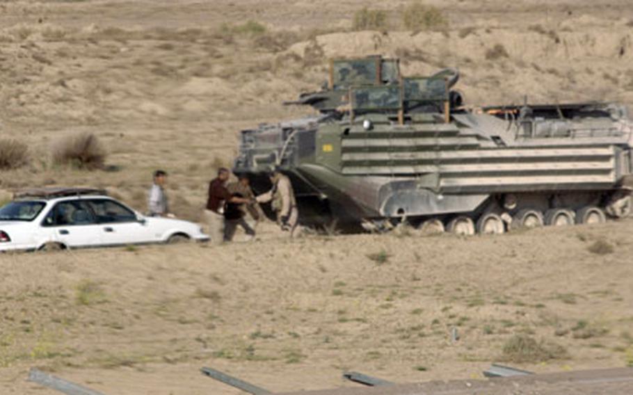 Staff Sgt. Richard Schmitt, 29, with 1st Platoon, Company B, Assault Amphibious Battalion, shakes hands with an Iraqi after helping tow the man’s car out of a sand pit Tuesday on a major highway east of Fallujah.