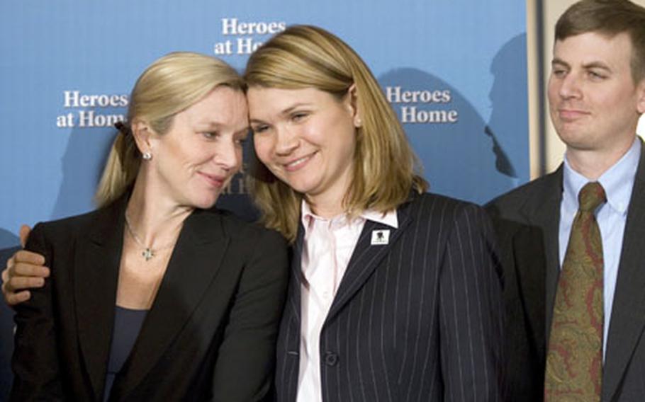 Two women who have been instrumental in helping their husbands recover from severe brain injuries incurred in Iraq — Lee Woodruff, left, and Sarah Wade — embrace during Thursday's news conference on Capitol Hill. At right is Sarah's husband, Sgt. Ted Wade.