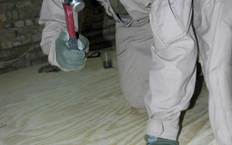 Combat Engineer Lance Cpl. Chris Houser, 25, of Providence Forge, Va., pounds nails into a floorboard that will serve as a sleeping area for soldiers living and working out of Out Post 3 in Karmah, Iraq, greatly improving the soldiers’ living conditions.