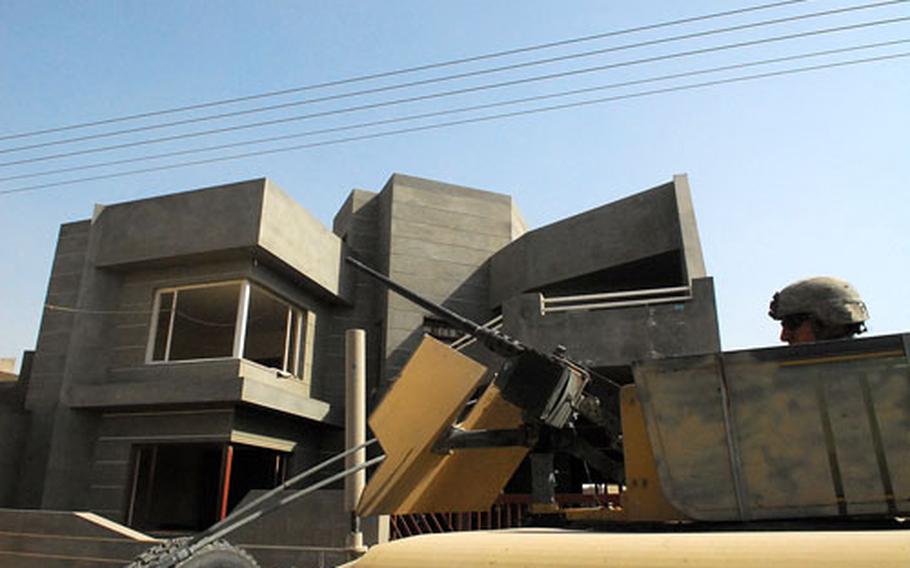 A Humvee rolls past one of many costly and newly constructed homes that have sprung up recently in the 9 Nissan Security District in east Baghdad.