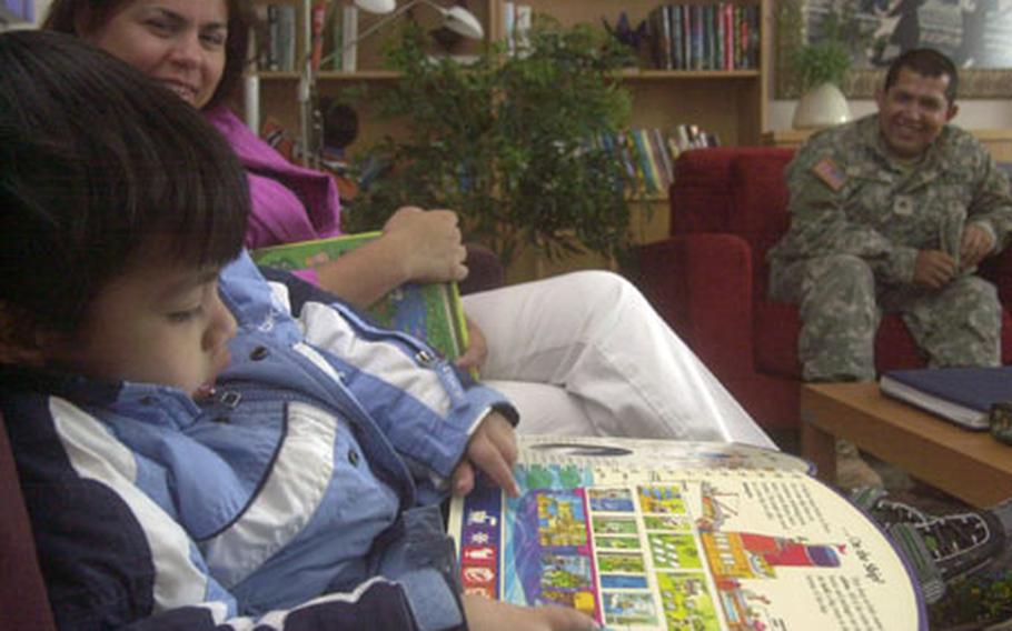 Three-year-old Fredy Zoque Jr. scans a book at one of two Fisher Houses on Landstuhl Regional Medical Center while his mother, Unice, and father look on.