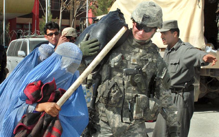 U.S. Army Maj. Arnold Strong, of Task Force Phoenix, assists local Afghan residents with relief supplies.