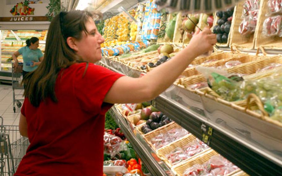 Teresa Dooms selects a few pieces of fruit Monday at the Defense Commissary Agency’s store at Aviano Air Base in Italy. Items produced in the States are a bigger bargain on base with the euro rising against the dollar.