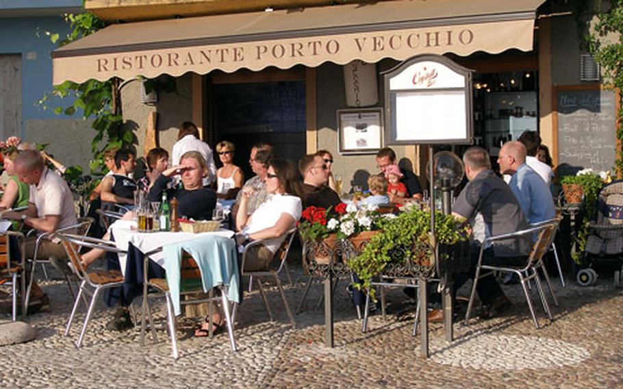 People enjoy the sun and cuisine on Lake Garda at a restaurant on the old port of the medieval town of Malcesine, Italy. According to Cambridge University researchers, Italians are the least happy people in Europe. (enw# 61p rb)