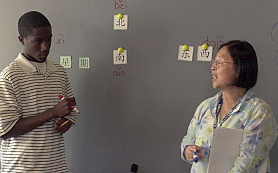 Standing at the blackboard, freshman Isaiah Haines, 14, listens as his Mandarin teacher Su-Lien Reinert tells him what to write.