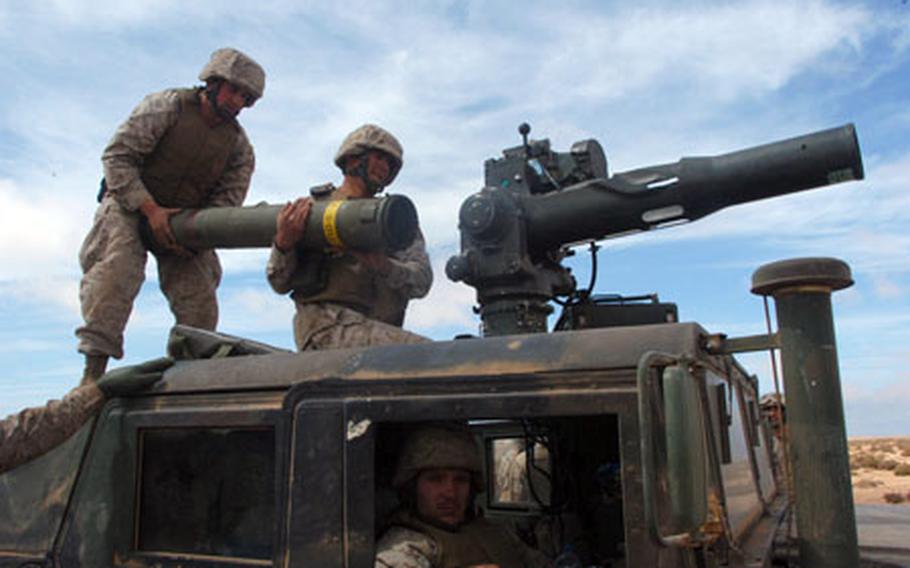 Lance Cpl. Alekzander Love, left, and Lance Cpl. Sean Conyers of Weapons Company, 2nd Battalion, 23rd Marine Regiment, load an optically tracked, wire-guided (TOW) missile into its launcher on Friday at Cap Draa Training Area, Morocco. Sitting in the Humvee is Lance Cpl. Aaron Reeder. The Marines were participating in African Lion 07, a two-week training exercise with the U.S. and Moroccan militaries.