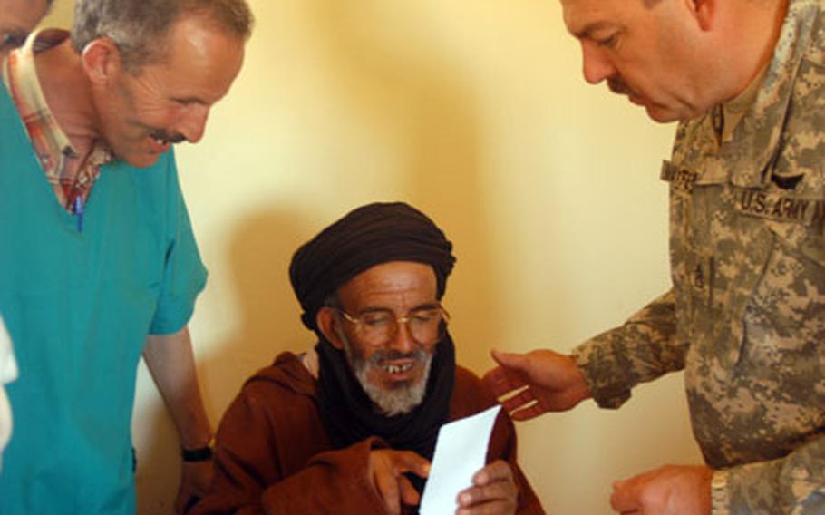 Staff Sgt. Steven Maxfield, right, of the Utah Army National Guard, and Oubaha Mohammed, a local nurse assistant, help a man test some eyeglasses Thursday during a U.S.-Moroccan military medical mission in Ben Khalil, Morocco.