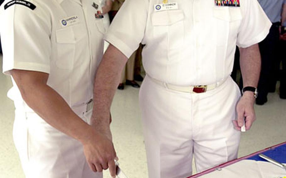 Seaman John Hammersla, left, a recent returnee from Iraq, and Capt. Peter F. O&#39;Connor, U.S. Naval Hospital Okinawa commander, make the first slice in a cake welcoming four sailors back from recent deployments to Iraq at a Warriors Welcome at the hospital Tuesday.
