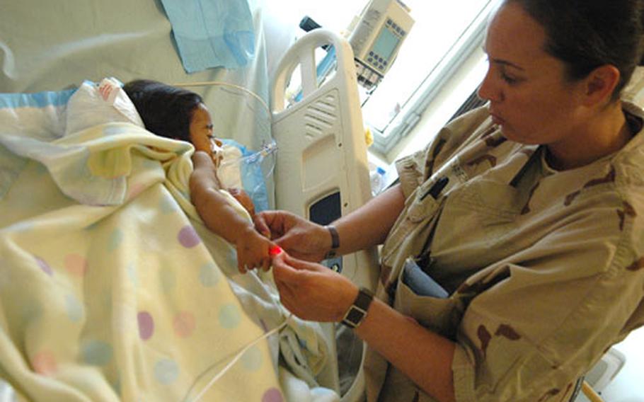 Army medic Michelle Chavez, 29, of Huntington Beach Calif., checks the temperature of a young Iraqi at the Ibn Sina Hospital intensive care ward in Baghdad's Green Zone on Tuesday.