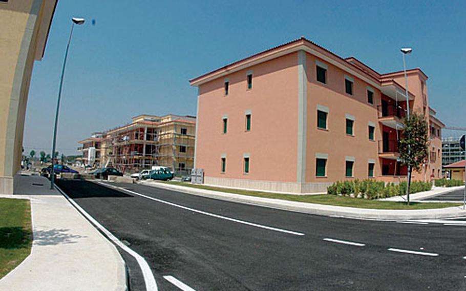 The salmon-colored building houses new, four-bedroom apartments for officers at the support site base in Gricignano, and behind it, construction crews work on a building of three-bedroom officer apartments.