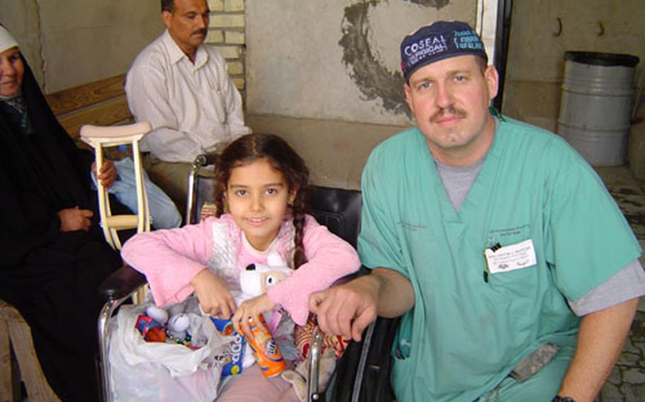 Staff Sgt. Victor Settles, a surgical technician at Ibn Sina Hospital in Baghdad's Green Zone, poses with one of the young Iraqi patients at the hospital.