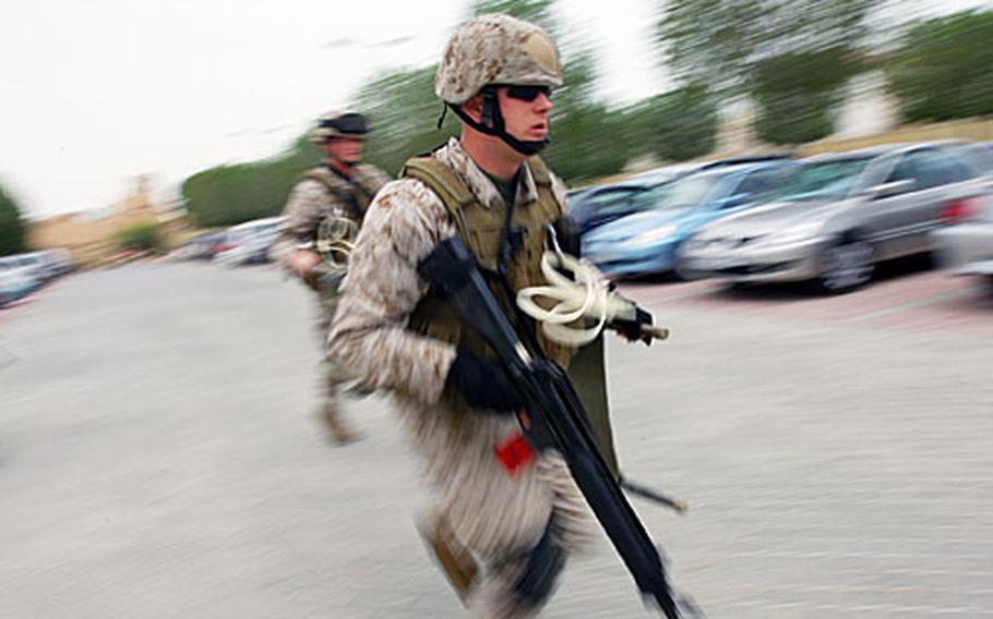 A U.S. Marine stationed at Naval Support Activity Bahrain rushes to the scene of a mock car explosion during a training exercise on the Navy base on Tuesday.