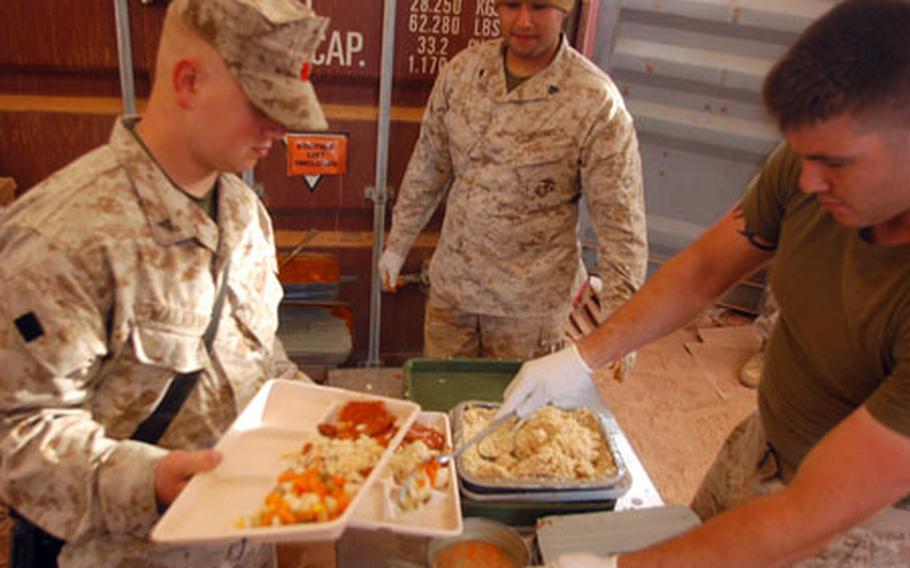 Lance Cpl. Matt Goldberg, right, of 2nd Battalion, 23rd Marine Regiment, and Sgt. Jesus Yepez, center, serve grub to Lance Cpl. Daniel Walraven, left, in the Logistic Support Area at Cap Draa Training Area in Morocco during African Lion 07, a joint training exercise between the U.S. and Moroccan militaries.