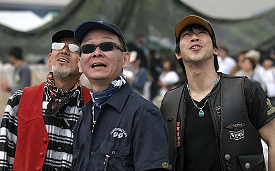 Three men "ooh" and "aah" as they stare skyward at one of the many aerial acts.