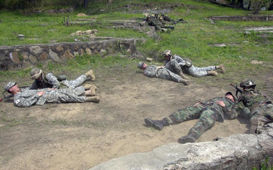 Soldiers low crawl toward injured victims during practice runs for the Expert Field Medical Badge at Warrior Base on Monday.