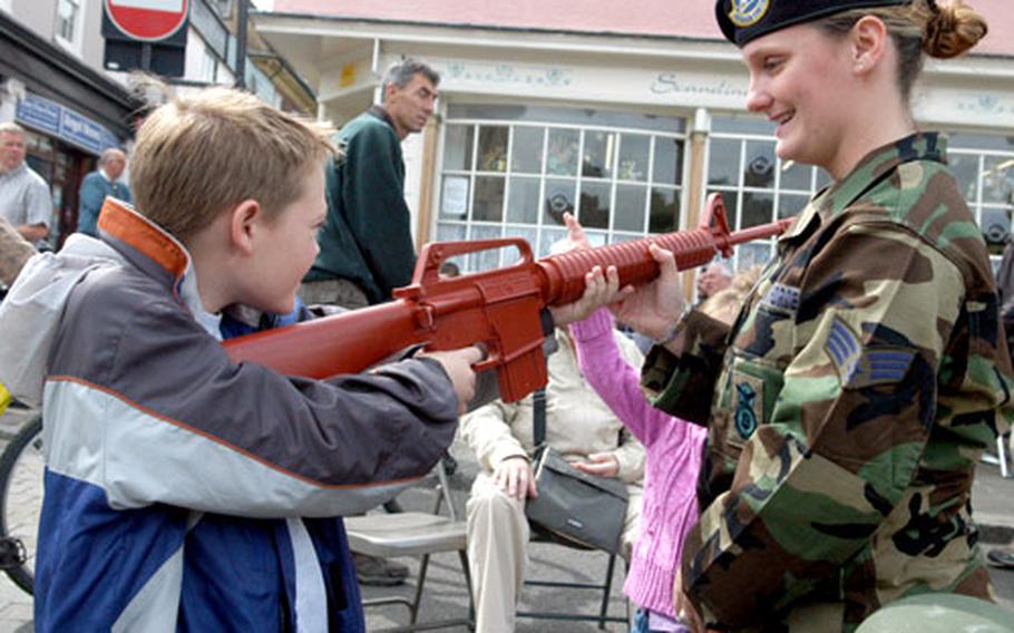 Senior Airman Angelina Dees of RAF Lakenheath&#39;s 48th Security Forces Squadron shows some local kids some training rifles the Air Force uses.