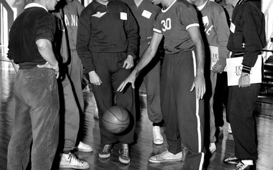 Bob Cousy demonstrates dribbling technique to a group or participants in the USAFE clinic.