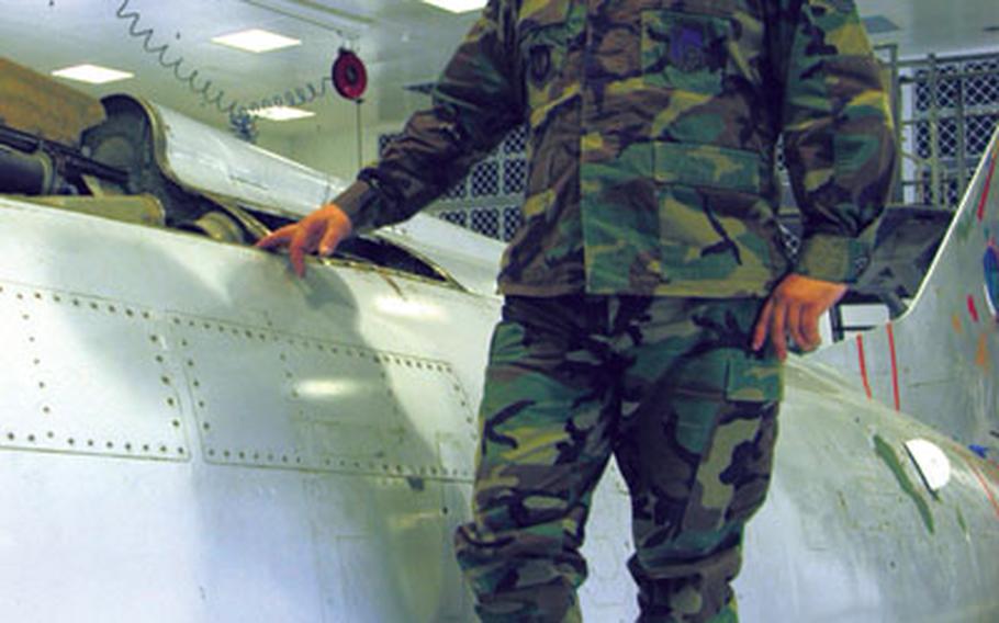 Tech. Sgt. Jeff Peets, 38, of Dover, N.H., stands on the wing of the 1954 F-100 fighter jet being refurbished at RAF Lakenheath.