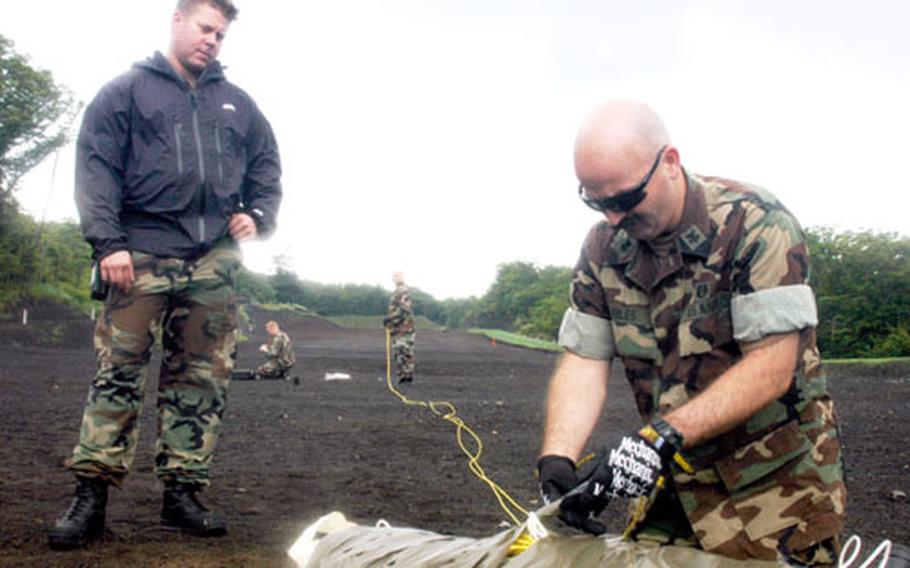 Chief Petty Officer Jason Kennedy, left, watches Petty Officer 1st Class Arick Hiles prepare 125 pounds of C-4 plastic explosive for detonation Monday at Camp Fuji, Japan. The members of Yokosuka Naval Base's explosive ordnance disposal detachment practice demolition training at Camp Fuji quarterly, they said.
