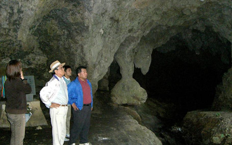 Haruo Chibana shows his young neighbors Shimuku Gama, a cornerstone of Yomitan’s Namihira district’s history. Residents used the cave as a bomb shelter during World War II. On the day U.S. forces landed Okinawa’s main island 62 years ago, 1,000 residents were about to commit mass suicide in fear of massacre by the “American beast,” but two men with firsthand knowledge of Americans averted the act.