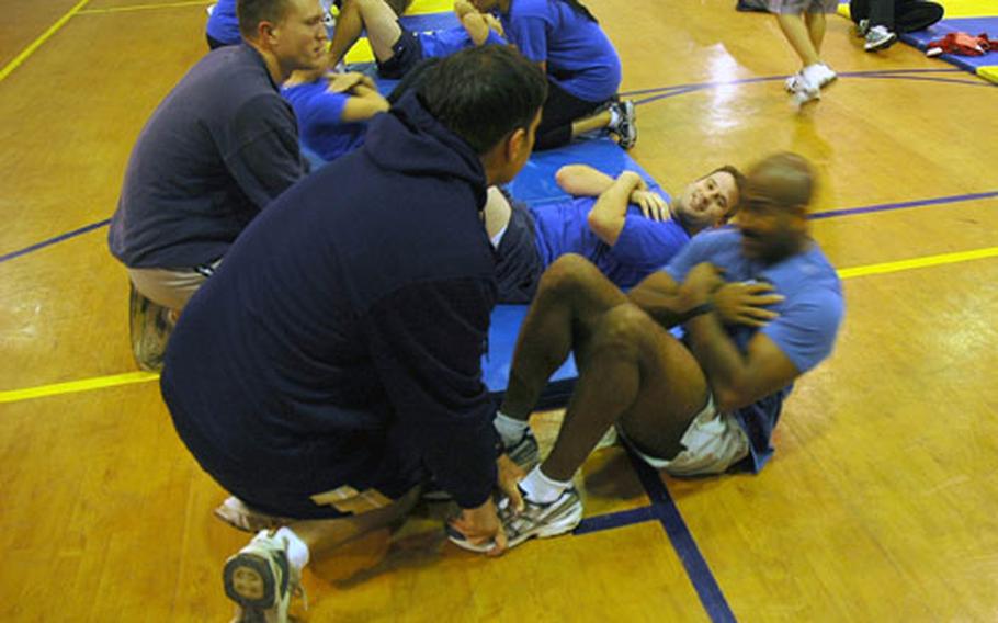 Cmdr. Reggie Howard, performs the curl-up portion of the Navy's semi-annual Physical Fitness Assessment held aboard Naval Air Station Sigonella. This summer, Navy Region Europe kicked off "Family Fitness," a new program that gets the entire family involved in physical fitness and healthy lifestyle practices.
