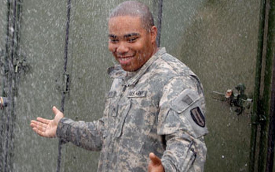 Pvt. John Johnson of 201st Signal Company, 1st Signal Brigade, tests the water coming out of a multipurpose decontamination system.