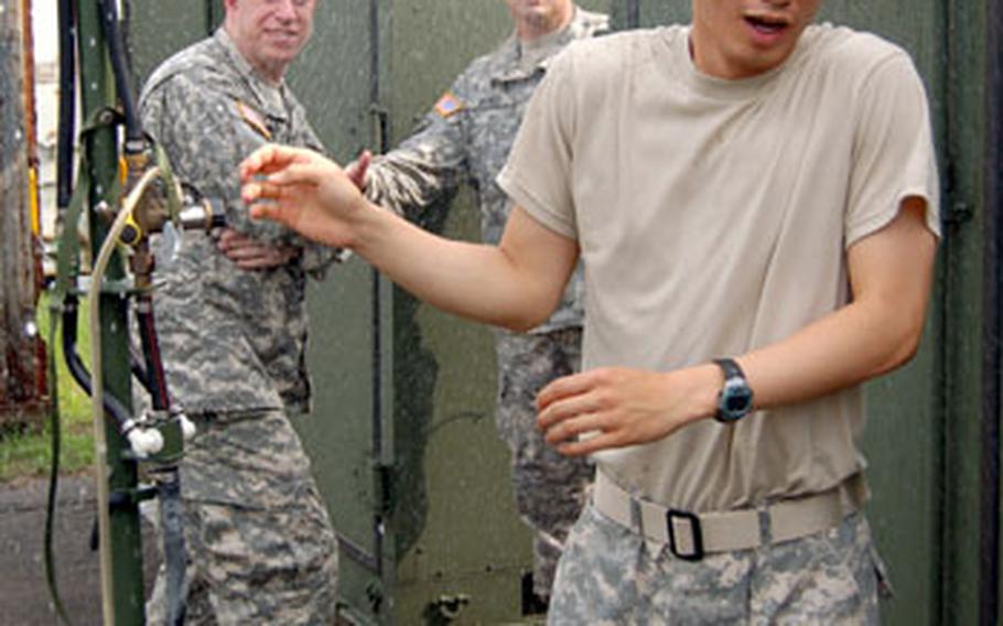 Cpl. Sohn Dong-kuen of 201st Signal Company, 1st Signal Brigade, tries to stay dry after turning on the multipurpose decontamination system.