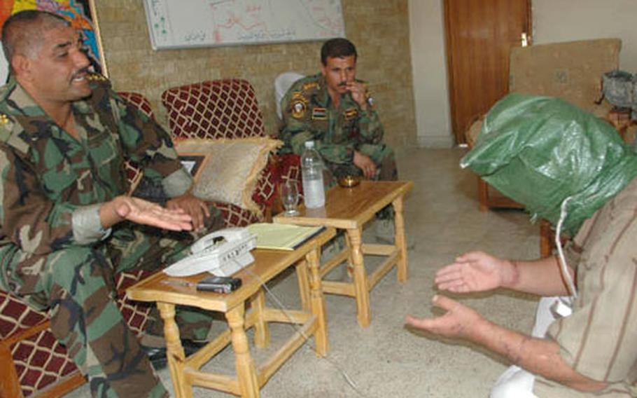 Iraqi police commander Abid Hamad Hasan, left, questions a suspected insurgent captured by the Iraqi police. Hasan said three of his men were killed the night before when they were checking cars at a crowded checkpoint.